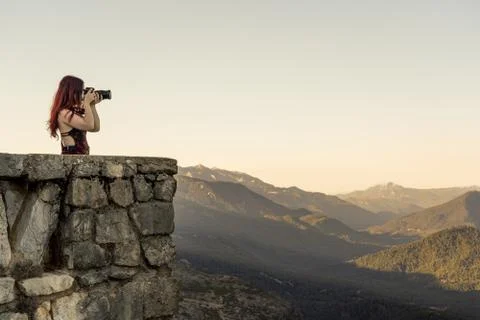 Girl using camera in balcony to take pictures from mountains Stock Photos