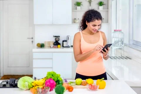 Girl using a cellphone while cooking in kitchen Stock Photos
