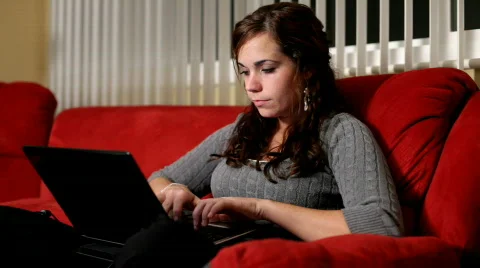 Girl using computer on red couch Stock Footage