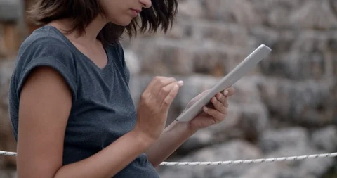 Girl using computer tablet on a beautiful rocky beach, close up, slow Stock Footage 118377713