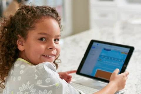 Girl using digital tablet looking over shoulder at camera smiling Stock Photos