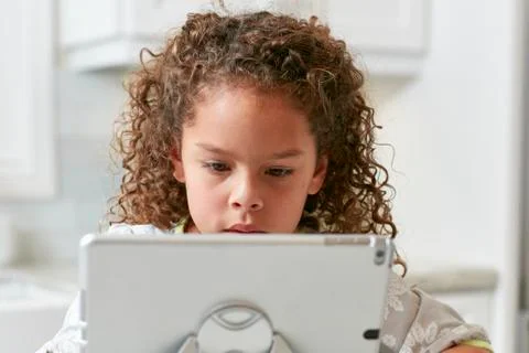 Girl using digital tablet looking down concentrating Stock Photos