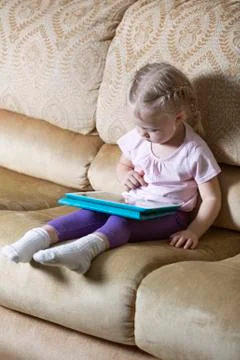 Girl using digital tablet on sofa Stock Photos