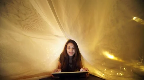 Girl using digital tablet under blanket while lying on bed at home Stock Footage 56314436