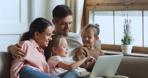 Girl using educational application on computer with sister and parents. Video stock 127827647