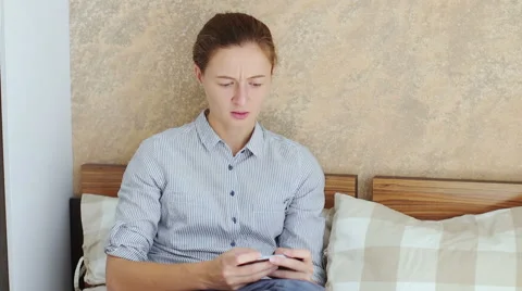 Girl using her smartphone while sitting down in bed Stock Footage 66469075