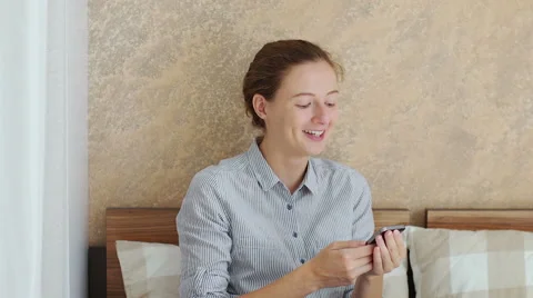 Girl using her smartphone while sitting down in bed 스톡 동영상 66469164