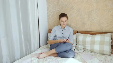 Girl using her smartphone while sitting down in bed Stock Footage 66469223