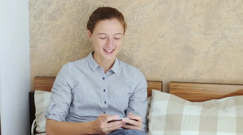 Girl using her smartphone while sitting down in bed Stock Footage 66469953