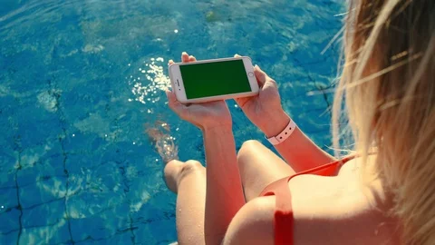 Girl using horizontal mobile phone green screen while relaxing near the swimming Stock Footage 105099997