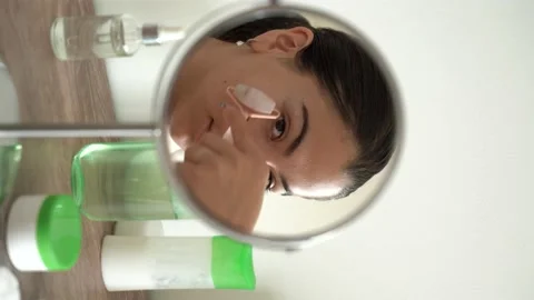 Girl using jade roller on face looking in the mirror. Rejuvenation treatment. Stock Footage 196658372