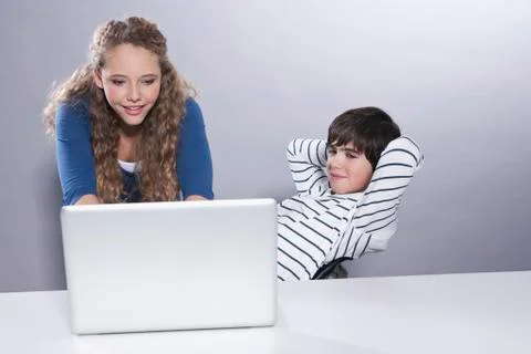 Girl using laptop while boy looking Foto stock