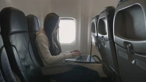 Girl using laptop while is sitting in plane near window Stock Footage 85835877