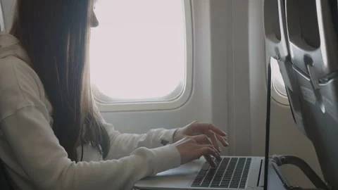 Girl using laptop while is sitting in plane near window Stock Footage 85835907