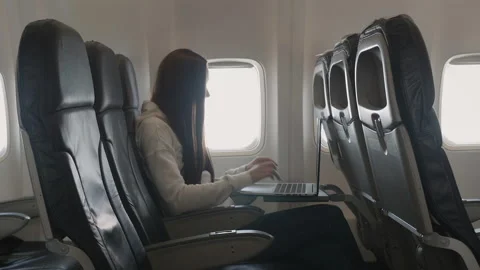 Girl using laptop while is sitting in plane near window Stock Footage 85835959