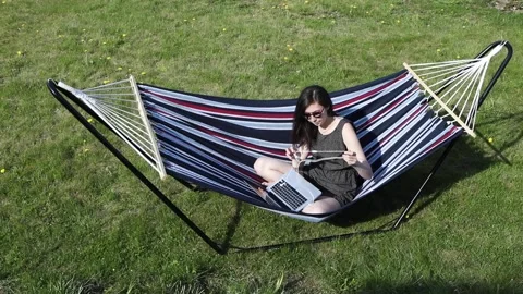 Girl using laptop while sitting in hammock. Stock Footage 131719934
