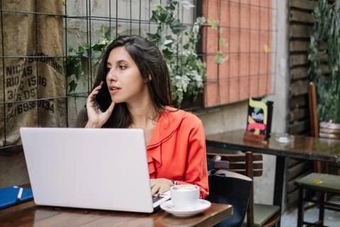 Girl using laptop while speaking on mobile phone Foto stock