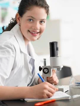Girl Using Microscope And Taking Notes Stock Photos