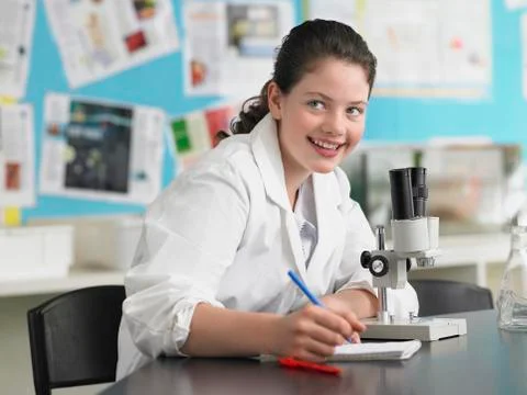 Girl Using Microscope And Taking Notes 写真素材