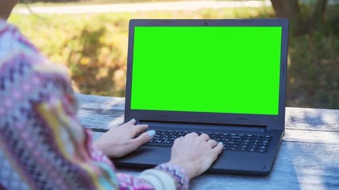 Girl Using NoteBook with Pre Keyed Green Screen Sitting on the Bench in City Stock Footage 72480409