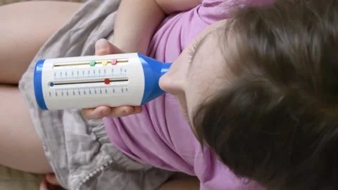 Girl using peak flow meter for lung function test while sitting on couch, Stock Footage 302381734