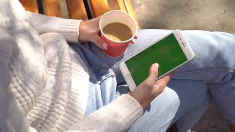 Girl using phone with chrona screen and drinks cofee Video stock 80807310