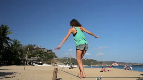 Girl using a slackline in the beach, her shadow projected in the sand. Stock Footage 49764559