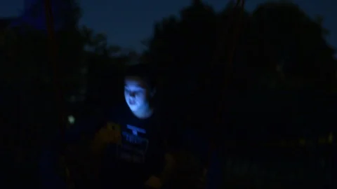 Girl using smart phone while riding on swing in nigth park. Selective focus.  Видео 94425808