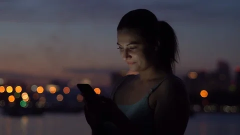 A girl is using a smartphone in the background of a night city. slow motion Stock Footage 91415079