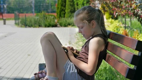 Girl is using smartphone on a bench in park Stock Footage