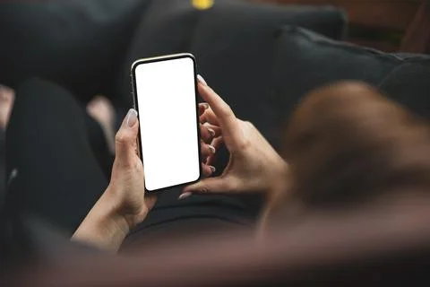 Girl using smartphone blank screen frameless modern design while lying on the Stock Photos