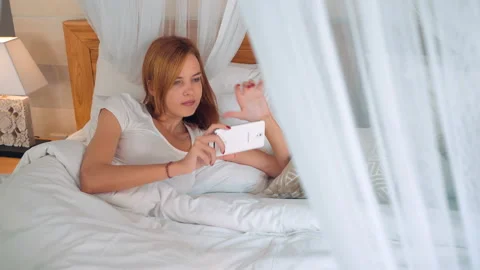 Girl using smartphone in canopy bed 動画素材 87731148