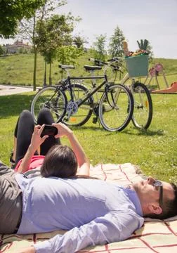 Girl using smartphone lying over man on the park Foto stock