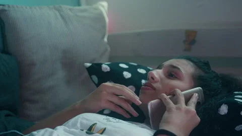 Girl using a smartphone while lying down in a dimly lit room Stock Footage 275010411