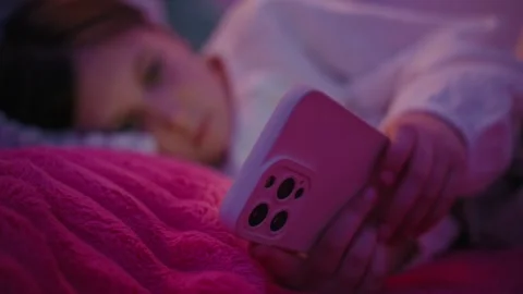 Girl Using Smartphone While Lying in Bed at Night Stock Footage 345528338