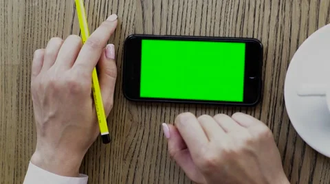 Girl using smartphone on wood table. Hand touching black color smart phone with Stock Footage