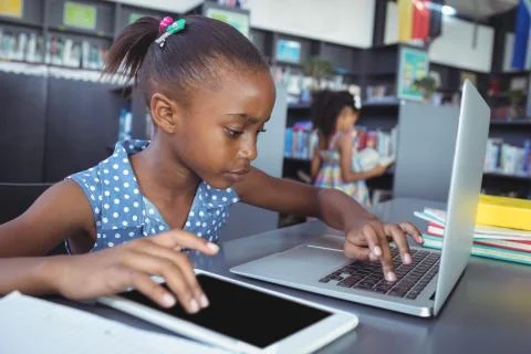Girl using tablet computer and laptop in library 스톡 사진