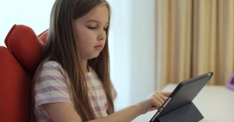 Girl using a tablet computer for learning at home in her childrens bedroom. Stock Photos