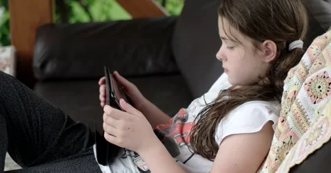 Girl Using Tablet Computer Lying on Leather Sofa on Terrace Stock Footage 64651263