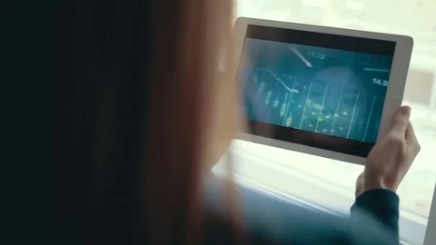 Girl using tablet computer tracks chart and the stock exchange in the background Stock-Footage 83262503