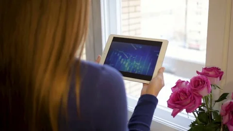 Girl using tablet computer tracks chart and the stock exchange in the background Stock Footage 83264583