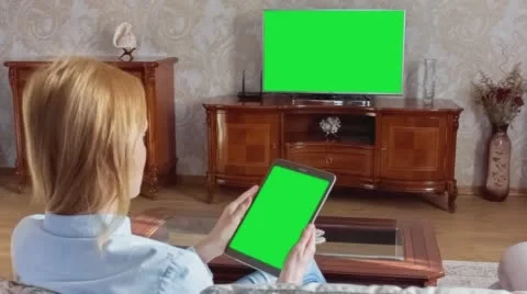 Girl Using Tablet In Front Of The TV With Green Screen  Stock Footage 64699484