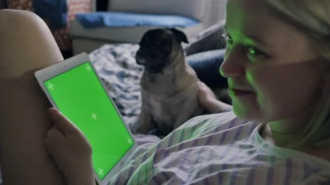 Girl is using tablet with green screen, near cute dog. Girl smiling Stock Footage 101429614