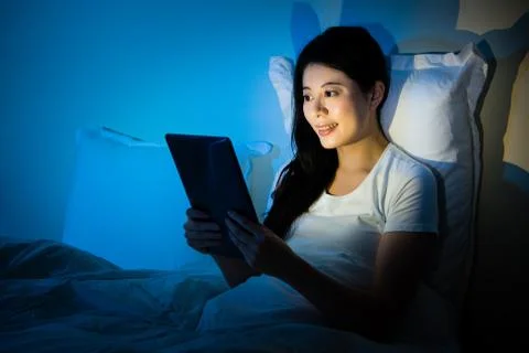 Girl using tablet pc in her bed at night Stockfoto's