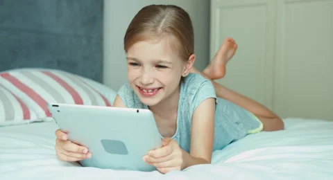 Girl using tablet pc lying on the bed and laughing at camera Video stock 53085289
