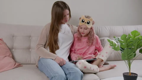A girl using a tablet while sitting by a young woman. Stock Footage 263640958