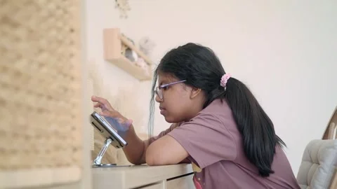 Girl using a tablet while sitting at a desk in a room Stock-Footage 346964057