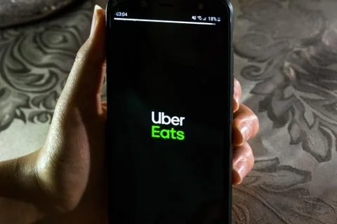 A girl using Uber Eats app on a smartphone to order food online Stock Photos