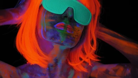 A girl with an UV pattern on her body, wearing an orange wig and green glasses. Stock Footage 265428928