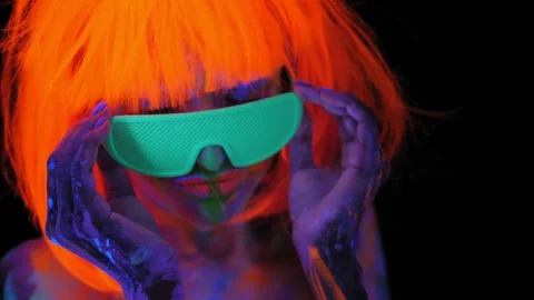 A girl with an UV pattern on her body, wearing an orange wig and green glasses. Stock Footage 265860232